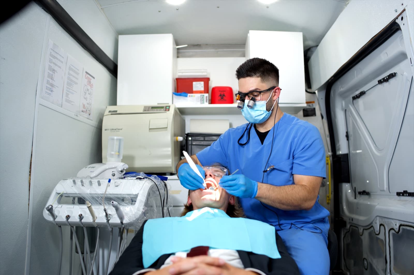 Dr. Milad Gheisari treating a patient inside the Las Vegas Mobile Dental Clinic van, with sterilization and portable dental equipment